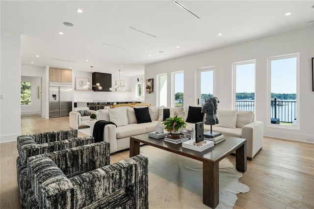 living room featuring a water view, plenty of natural light, and light hardwood / wood-style floors