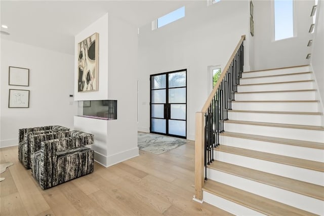 entryway featuring a towering ceiling and light hardwood / wood-style flooring