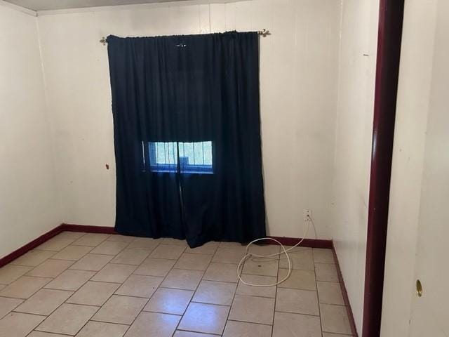 unfurnished room featuring light tile patterned floors and baseboards