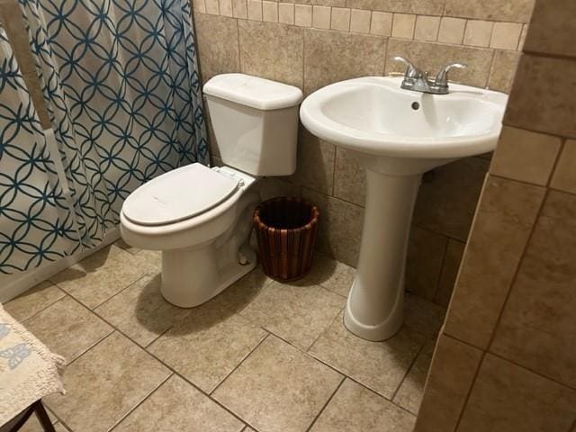 bathroom featuring tile patterned flooring, toilet, a shower with shower curtain, and tile walls