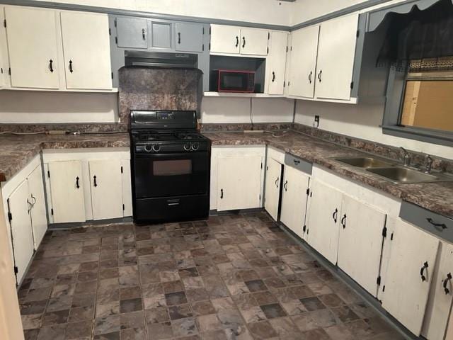 kitchen with under cabinet range hood, black appliances, dark countertops, and a sink