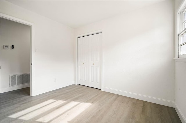 unfurnished bedroom featuring a closet and light hardwood / wood-style flooring