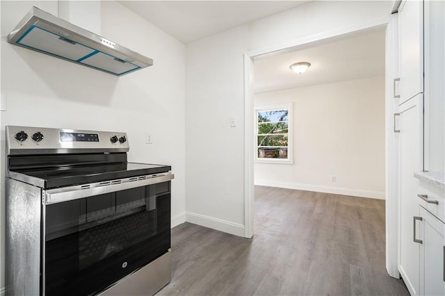 kitchen with stainless steel electric range oven, hardwood / wood-style floors, white cabinets, and extractor fan