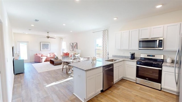 1249 Legacy Rd, Mobile, AL 36608 - kitchen with stainless steel appliances, a sink, a peninsula, light stone counters, and light wood-type flooring
