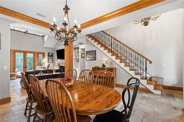 dining space featuring a chandelier, a high ceiling, a raised ceiling, crown molding, and french doors