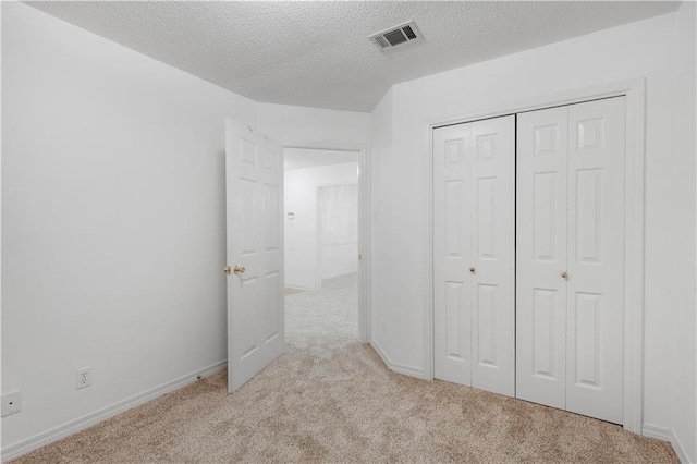 unfurnished bedroom featuring a closet, light carpet, and a textured ceiling