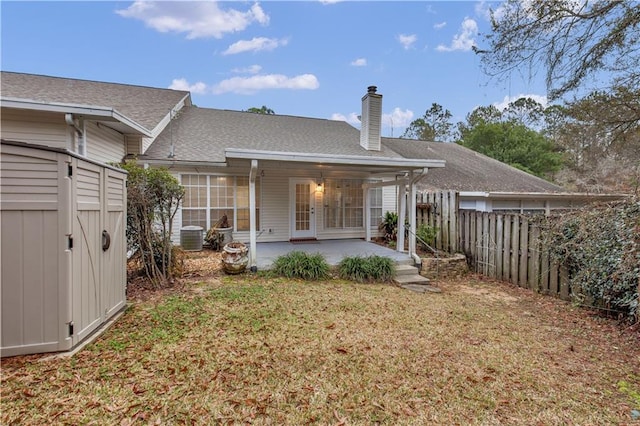 rear view of property with central AC unit, a patio area, and a lawn