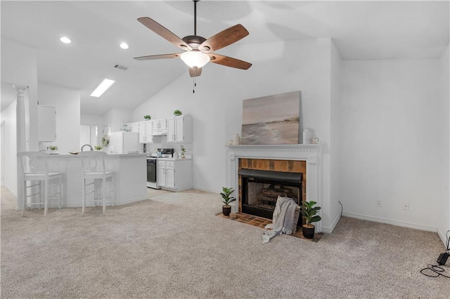 carpeted living room featuring vaulted ceiling, ceiling fan, and a fireplace