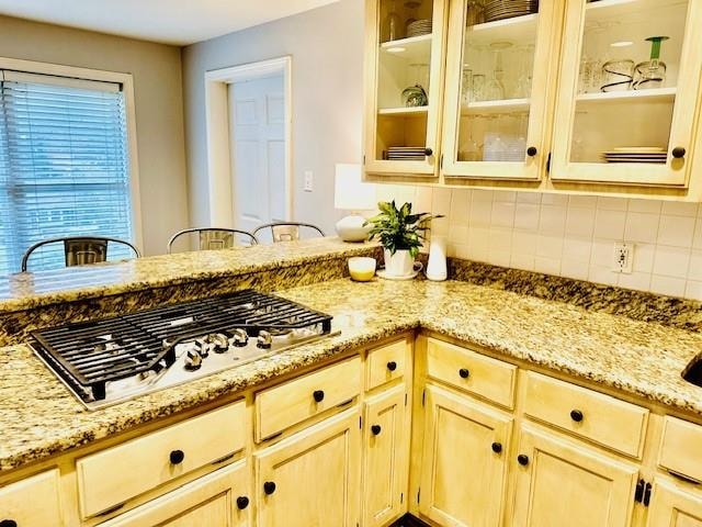 kitchen featuring stainless steel gas cooktop, light stone countertops, light brown cabinetry, and tasteful backsplash