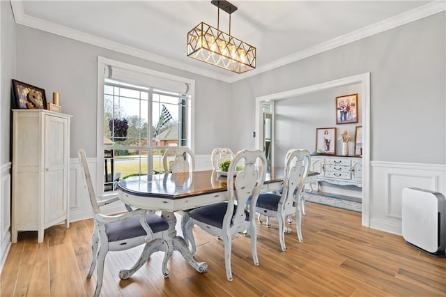 dining space with an inviting chandelier, ornamental molding, and light hardwood / wood-style floors