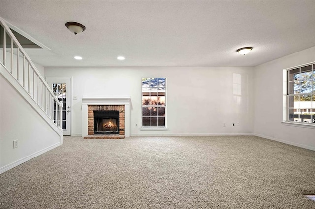 unfurnished living room with carpet flooring, a fireplace, and a textured ceiling