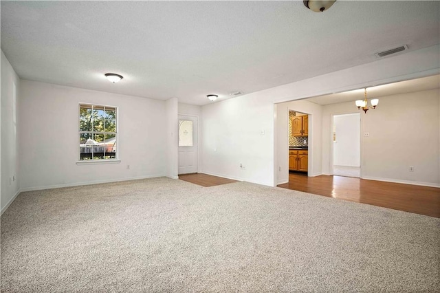 carpeted spare room featuring a chandelier