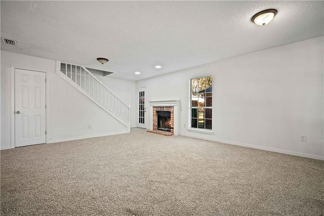 unfurnished living room featuring carpet, a textured ceiling, and a brick fireplace