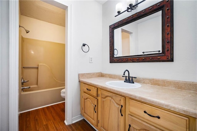 full bathroom featuring hardwood / wood-style floors, vanity,  shower combination, and toilet