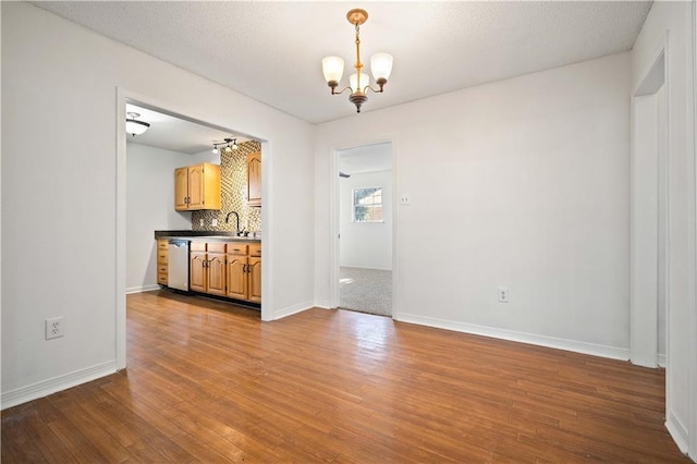 unfurnished dining area with sink, wood-type flooring, and a notable chandelier