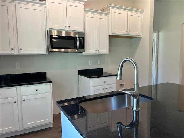 kitchen with sink, a center island, dark wood-type flooring, dark stone counters, and white cabinets