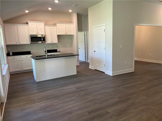 kitchen featuring white cabinetry, sink, dark hardwood / wood-style floors, lofted ceiling, and a kitchen island with sink