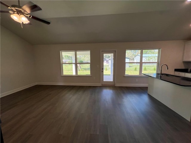 unfurnished living room with ceiling fan, sink, dark wood-type flooring, and vaulted ceiling