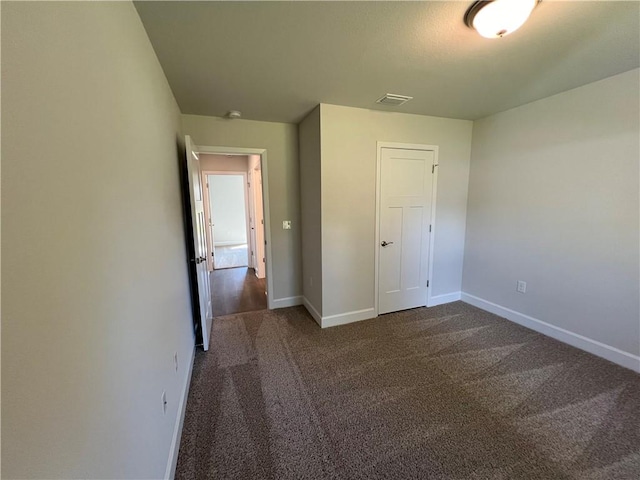 unfurnished bedroom with dark carpet and a closet