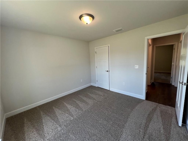 unfurnished bedroom featuring dark colored carpet and a closet