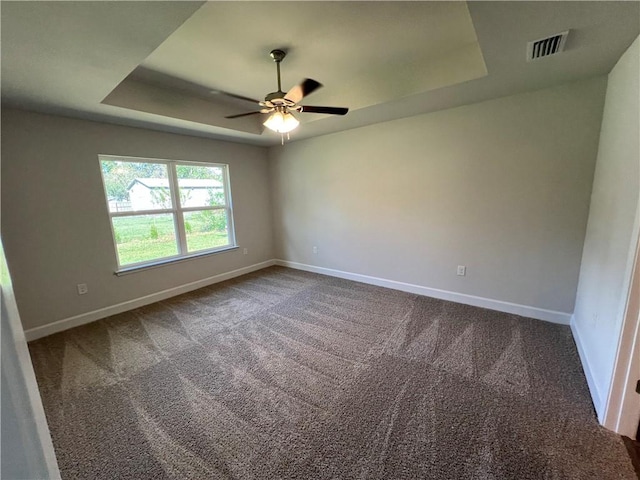 carpeted empty room featuring ceiling fan and a raised ceiling