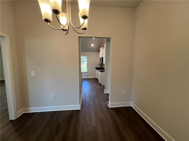 unfurnished dining area featuring dark hardwood / wood-style floors and an inviting chandelier