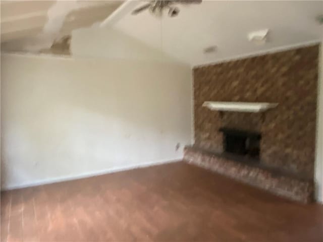 unfurnished living room featuring ceiling fan and a large fireplace