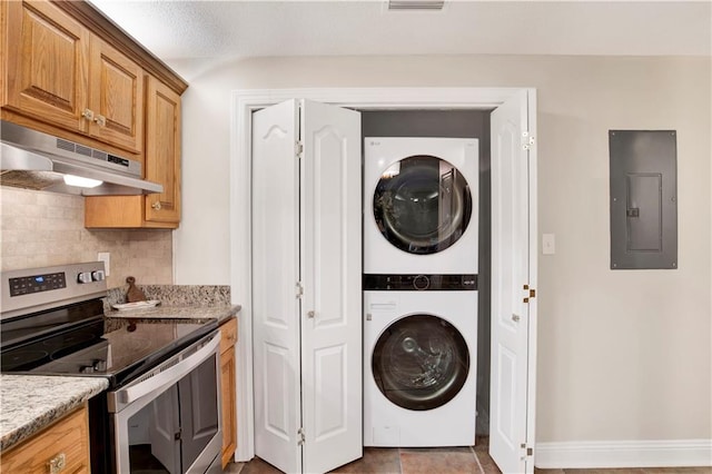 clothes washing area with electric panel and stacked washing maching and dryer