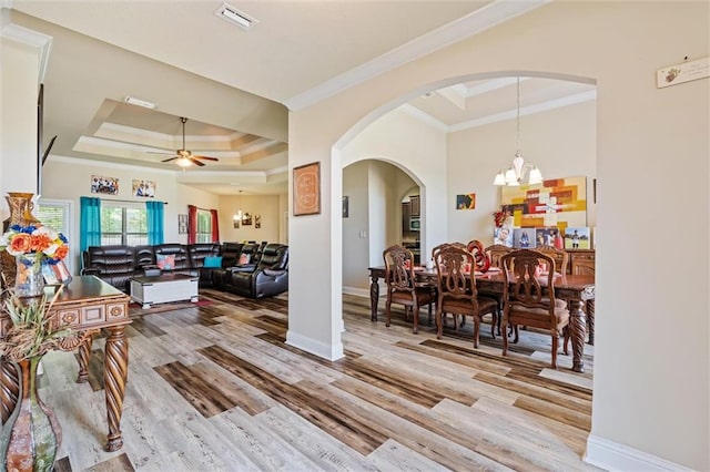 interior space with ceiling fan with notable chandelier, light hardwood / wood-style floors, a raised ceiling, and crown molding