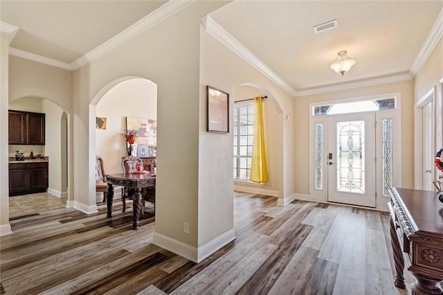 foyer entrance featuring crown molding, hardwood / wood-style floors, and a healthy amount of sunlight