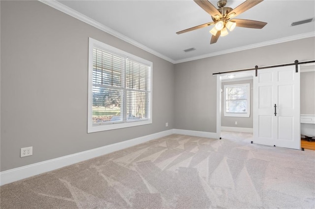 unfurnished bedroom with multiple windows, ceiling fan, ornamental molding, and a barn door