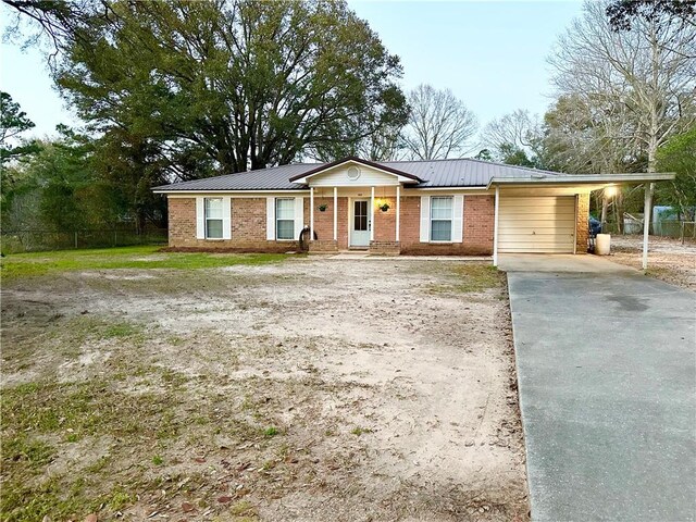ranch-style home featuring metal roof, driveway, brick siding, and an attached garage