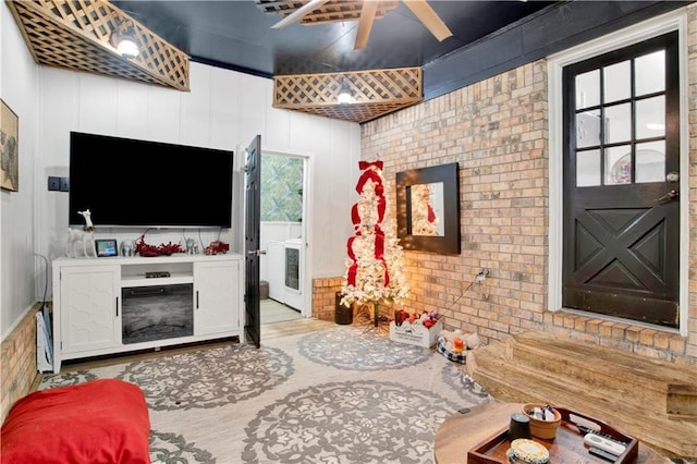 living room with ceiling fan, brick wall, and light hardwood / wood-style floors