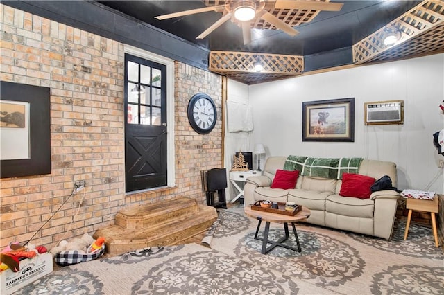 living room featuring ceiling fan, a wall mounted AC, and brick wall