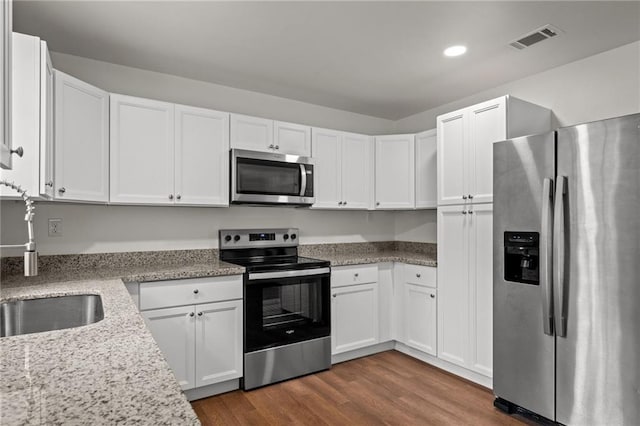 kitchen with dark wood-style floors, visible vents, a sink, white cabinets, and appliances with stainless steel finishes