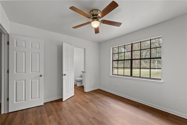 unfurnished bedroom with connected bathroom, a ceiling fan, baseboards, and wood finished floors