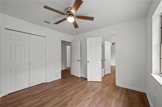 unfurnished bedroom with a closet, visible vents, baseboards, and wood finished floors