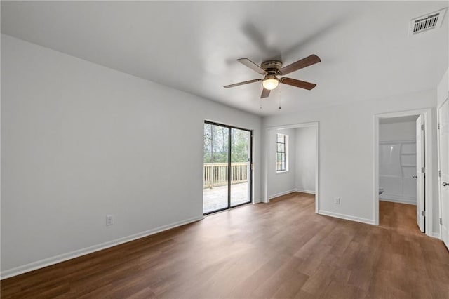 empty room featuring a ceiling fan, wood finished floors, visible vents, and baseboards