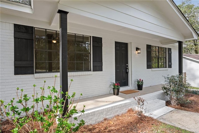 doorway to property featuring brick siding and a porch