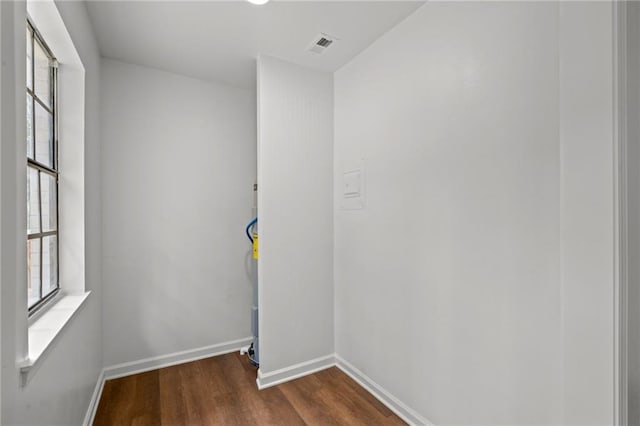 unfurnished room featuring dark wood-style floors, plenty of natural light, visible vents, and baseboards