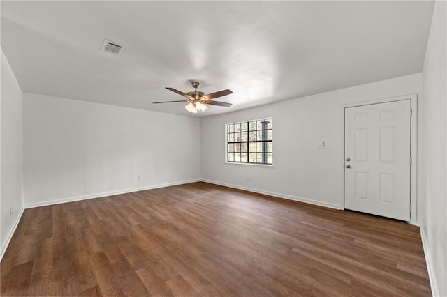 unfurnished room with ceiling fan, visible vents, baseboards, and dark wood-style floors