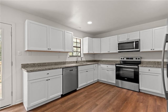 kitchen with dark wood-style flooring, white cabinets, stainless steel appliances, and a sink