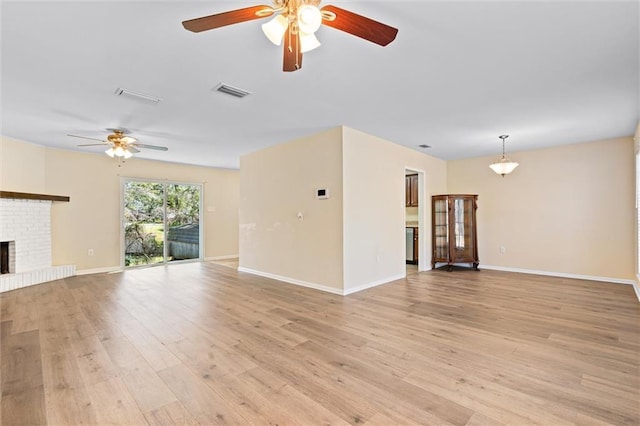 unfurnished living room featuring a fireplace, light wood finished floors, visible vents, a ceiling fan, and baseboards