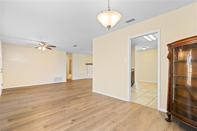 empty room featuring light wood-type flooring, baseboards, visible vents, and a ceiling fan