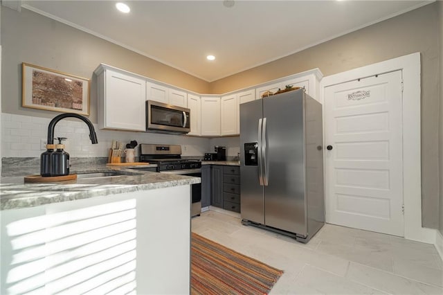 kitchen with white cabinets, sink, decorative backsplash, ornamental molding, and appliances with stainless steel finishes