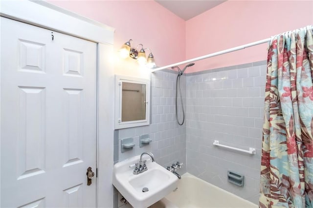 bathroom with shower / bathtub combination with curtain and sink