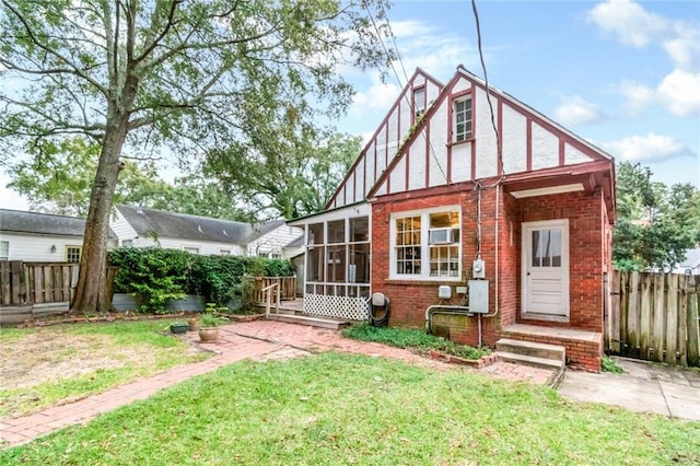 back of house featuring a lawn and a sunroom