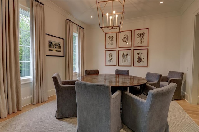 dining area with an inviting chandelier, crown molding, and light hardwood / wood-style flooring