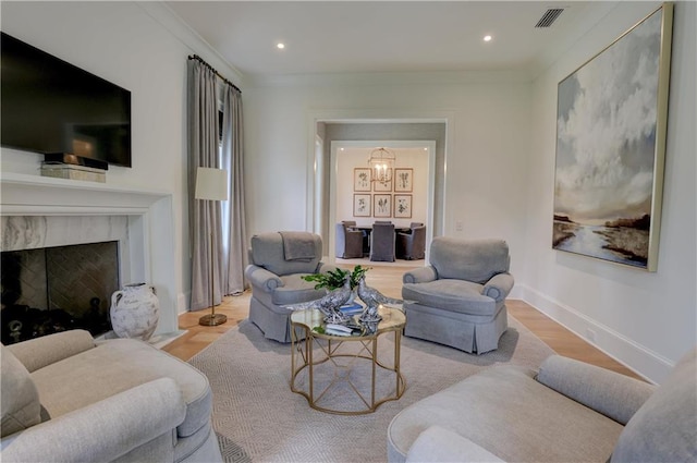 living room with ornamental molding, a fireplace, and light hardwood / wood-style flooring