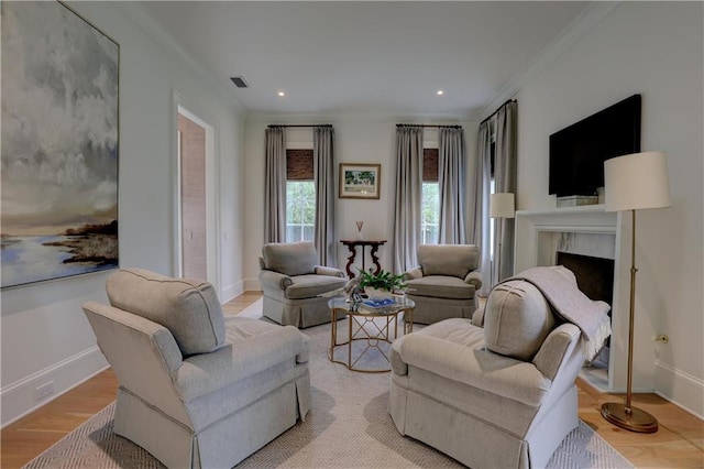 sitting room featuring a fireplace, ornamental molding, and light wood-type flooring